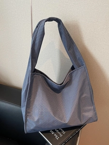 Grand sac cabas à carreaux bleus avec large bandoulière sur un canapé noir élégant