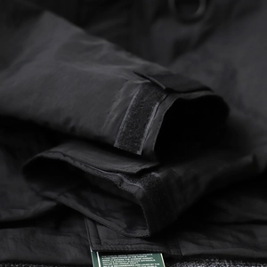 Detail view of adjustable Velcro cuff on a black waterproof outdoor techwear jacket