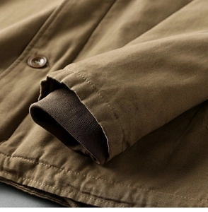 Detail of khaki canvas jacket cuff with brown ribbed windproof sleeve and stitching