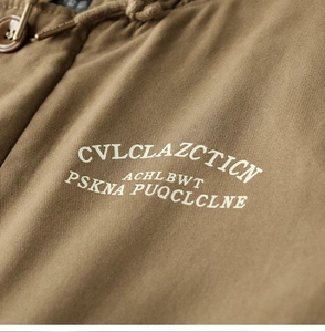 Detailed macro view of khaki canvas jacket showing twill texture and white graphic print