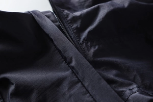 Close-up of durable black techwear jacket zipper with windproof fabric texture