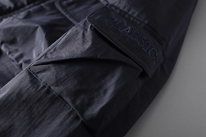 Detail of dark blue cargo jacket pocket with classic embroidery and waterproof fabric