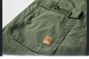 Detail of olive green outdoor vest flap pocket with Velcro and leisure leather patch