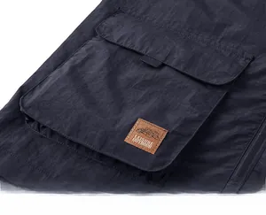 Detail of outdoor utility vest showing large flap pocket and leather brand patch