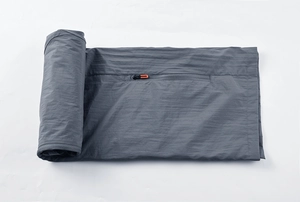Detail of grey quick-dry fabric showing a hidden zipper with orange puller for outdoors
