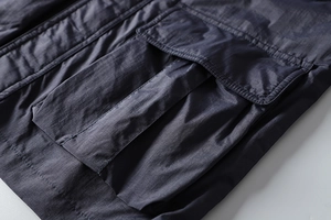 Detail of dark blue waterproof outdoor jacket featuring a large 3D cargo pocket with flap