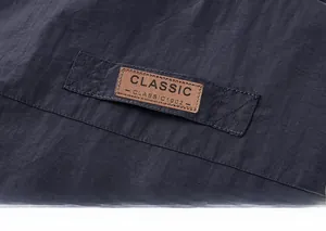 Macro shot of a classic brown leather patch with stitching detail on a navy cargo vest