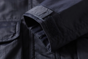 Detail of adjustable hook-and-loop cuff on deep navy blue outdoor functional jacket