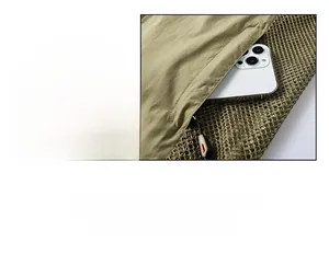 Detail of khaki outdoor vest showing zipper pocket with phone and mesh panel