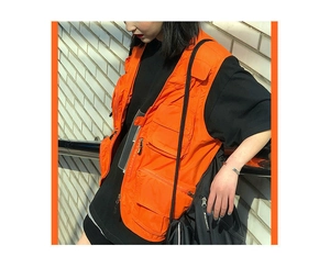 Detail of orange multi-pocket tactical vest featuring functional zippers and flap pockets