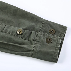 Détail du poignet d'une chemise en coton vert militaire avec boutons métalliques gravés