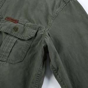 Détail d'une chemise en coton vert armée avec patch extérieur en cuir et bouton en laiton