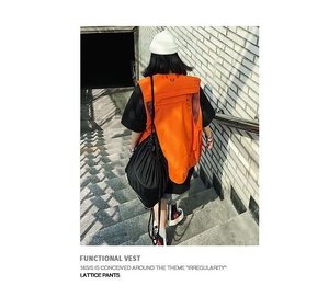 Outdoor street view of orange functional vest with multiple pockets and mesh panels