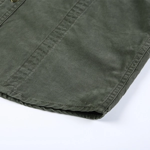 Détail d'une chemise cargo vert armée en coton avec coutures renforcées et bouton en métal