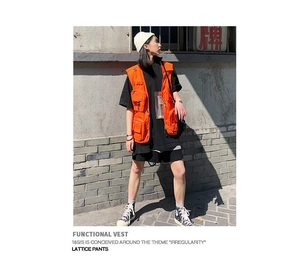 Close-up of bright orange multi-pocket tactical vest with clear PVC insert for outdoor hiking