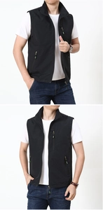 Detail of black outdoor vest with zippered pockets and neon green puller accents
