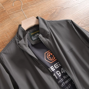 Détail d'une veste grise pour homme avec col montant, étiquette et logo imprimé sur la poitrine