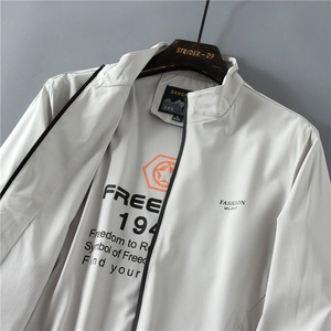 Dettaglio giacca grigio chiaro con collo alto, stampa Fashion Milano e zip