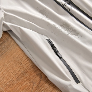 Gros plan du tissu imperméable d'une veste d'extérieur avec gouttes d'eau et fermeture