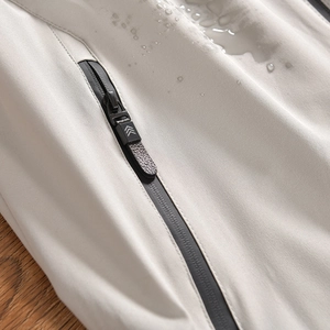 Détail de la veste d'extérieur gris clair avec tissu déperlant et fermeture éclair étanche