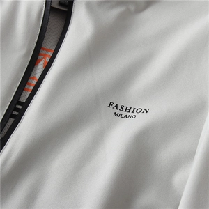 Dettaglio giacca grigia con stampa Fashion Milano, fodera in rete arancione e zip in resina