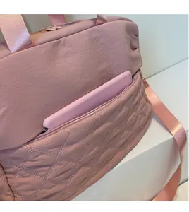 Detail of pink quilted gym bag featuring a functional front zipper pocket for a tablet