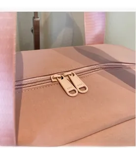Detailed close-up of high-quality SBS brand metal zippers on a pink travel bag