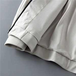 Dettaglio della zip nera, fodera in mesh e polsini a coste sulla giacca color beige