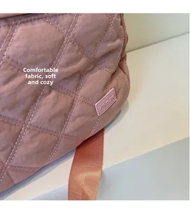 Close-up of pink quilted fabric texture and rubber logo tag on a large travel bag