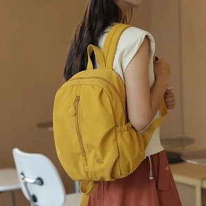 Side view of model wearing a bright yellow waterproof nylon backpack for travel and school
