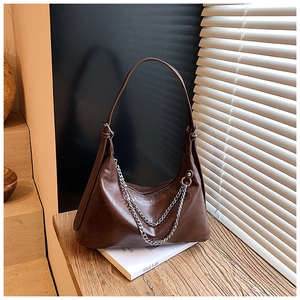 Detail of dark brown leather hobo bag with double silver chain and minimalist strap