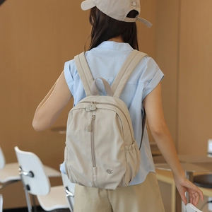 Detail view of beige nylon backpack texture with side elastic pocket and secure zippers