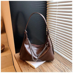 Detail of dark brown leather hobo bag with silver chain strap on a wooden surface