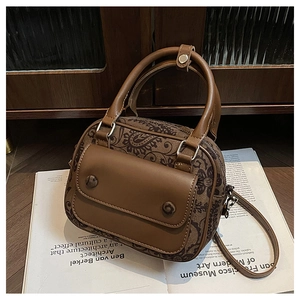 Close-up of vintage brown paisley patterned crossbody bag on a white magazine