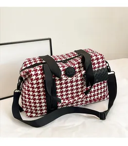 Macro shot of red houndstooth weave fabric and black rubber logo on travel bag