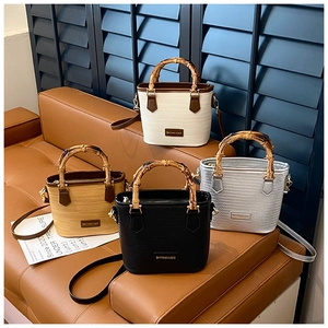 Detail of woven straw bucket bags in four colors featuring bamboo handles and leather straps