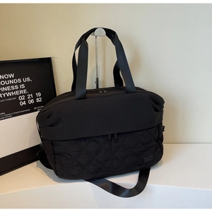 Detail of black large travel bag with diamond quilted stitching and adjustable shoulder strap