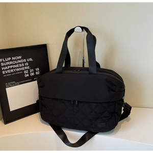 Detail of a black large capacity tote with quilted texture and adjustable nylon strap