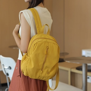 Close-up of a stylish yellow nylon backpack with multi-pocket design on female model