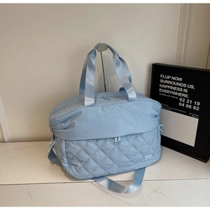 Detail view of light blue travel bag featuring diamond-quilted pattern and nylon handles