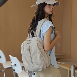 Detail view of large beige nylon travel backpack with waterproof zippers and side pocket