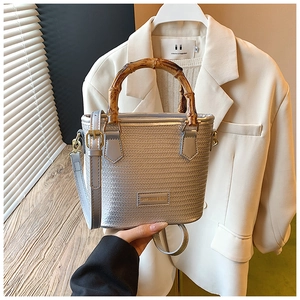 Detail of silver woven bucket bag featuring a vintage bamboo handle and gold hardware