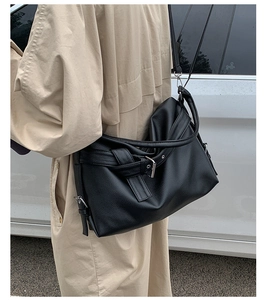 Close-up of black lychee grain leather tote bag with adjustable metal buckle strap