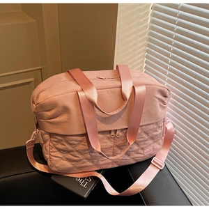 Detail of pink large travel bag with quilted diamond pattern and nylon fabric texture