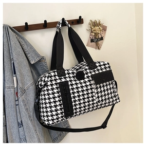 Detail view of houndstooth travel bag with front zipper pocket and adjustable strap