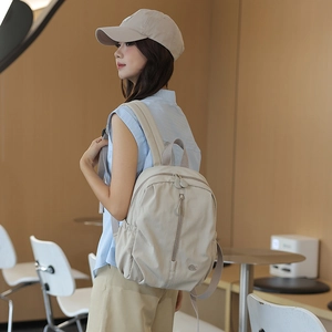 Beige waterproof nylon backpack shown from a side view in a modern cafe setting