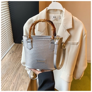 Detail of silver woven bucket bag with bamboo handle and adjustable shoulder strap