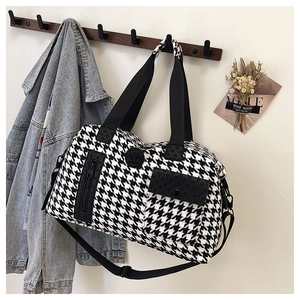 Detail showing houndstooth travel bag hanging on a hook with adjustable shoulder strap