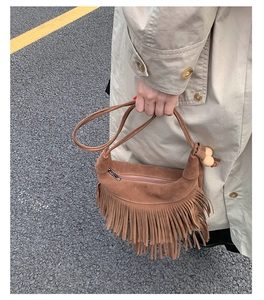 Détail d'un sac bohème en daim marron avec des franges élégantes et perles en bois