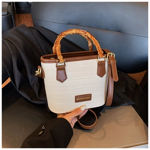 Detail of woven texture with roasted bamboo handle and brown leather strap on bag